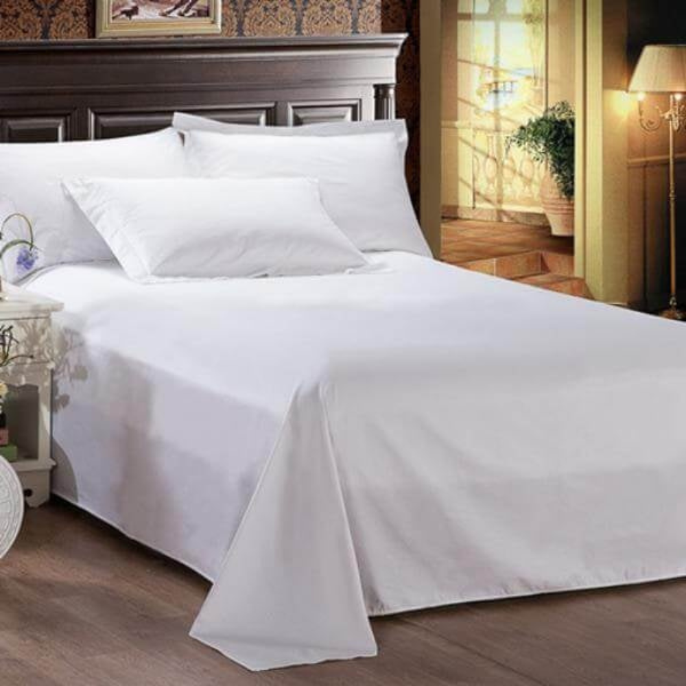 Comfortable bed with premium white bedsheet and soft white pillows with a lamp on the right hand side of the room entrance.