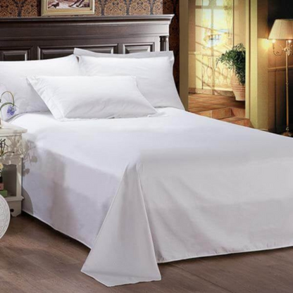 Comfortable bed with premium white bedsheet and soft white pillows with a lamp on the right hand side of the room entrance.