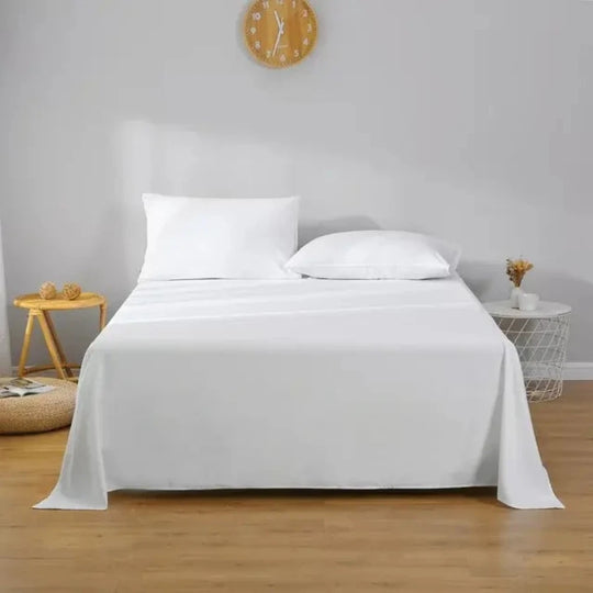 A comfortable bed with clean white bedding and soft white pillows having side table on both the sides close to wall.